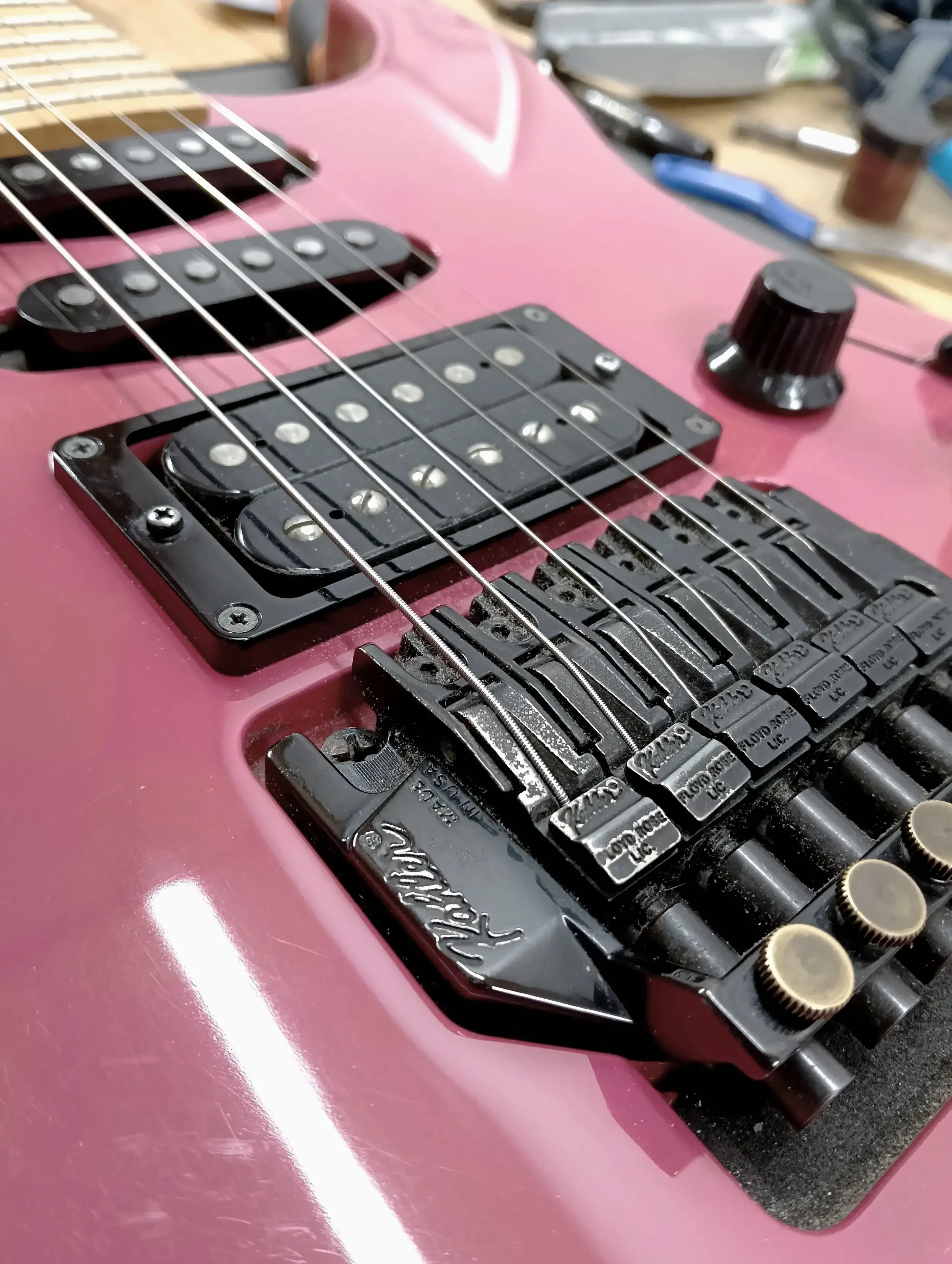 Close-up van een roze gitaar met een Floyd Rose-tremolo, een humbucker en een single coil, na het afstellen.